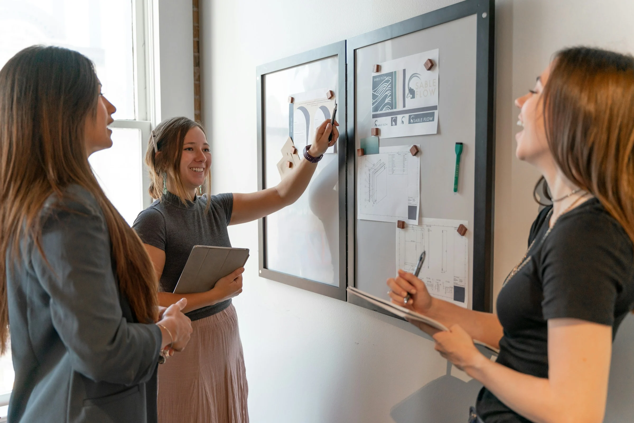 Drei Frauen stehen vor einem Board und arbeiten gemeinsam an einer Frage